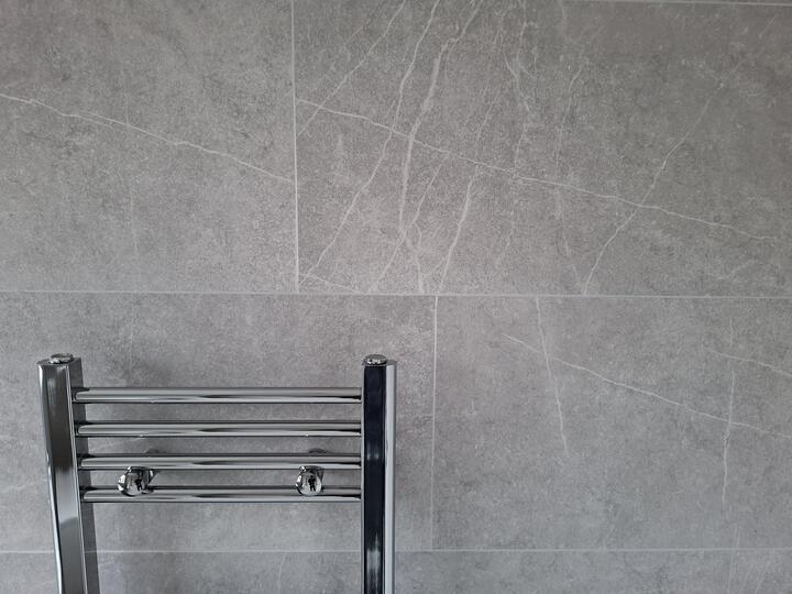 Large marble-effect tiles around a heated towel rail