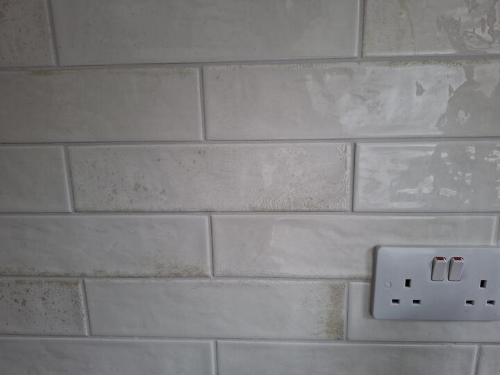 Close-up of glossy metro tiles with straight grout lines and a socket cut-out