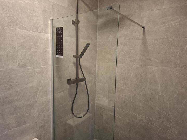 Walk-in shower with a frameless glass panel and marble-effect wall tiles